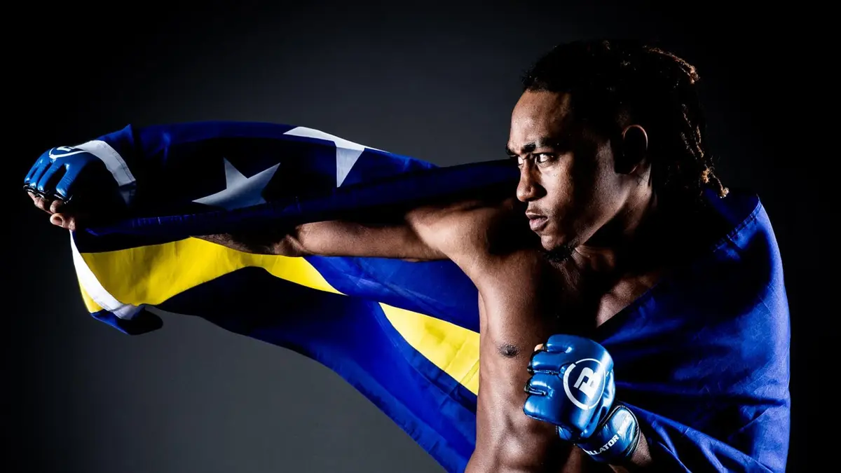 MMA fighter Brian Hooi in a fighting stance, holding a blue and yellow flag behind him